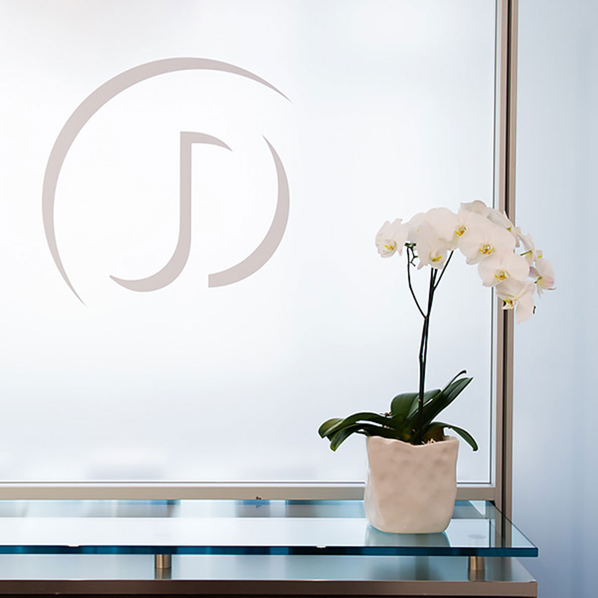 Picture of DeRosa Facial Plastic Surgery logo on window and a flower in a pot.