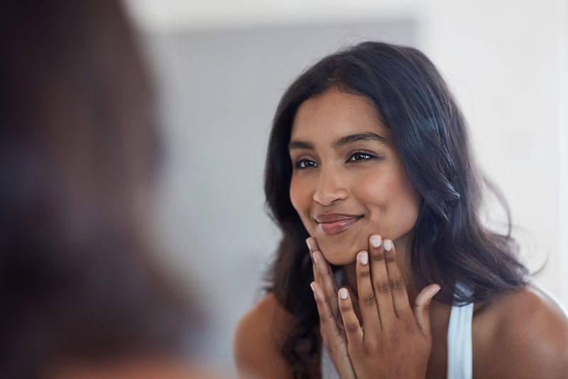 woman looking in the mirror after getting a chemical peel in Boston, MA