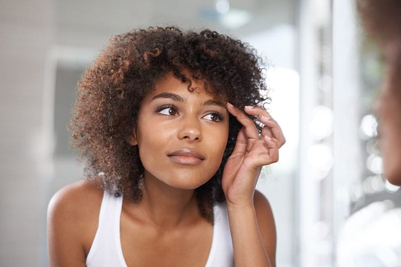 woman looking in the mirror after her brow lift in Boston, MA